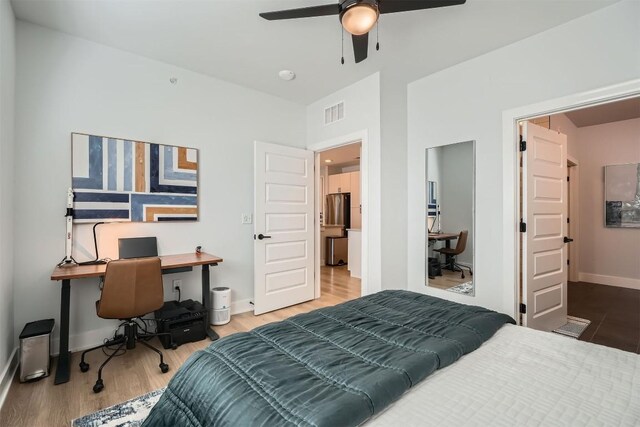 bedroom featuring visible vents, baseboards, ceiling fan, wood finished floors, and freestanding refrigerator