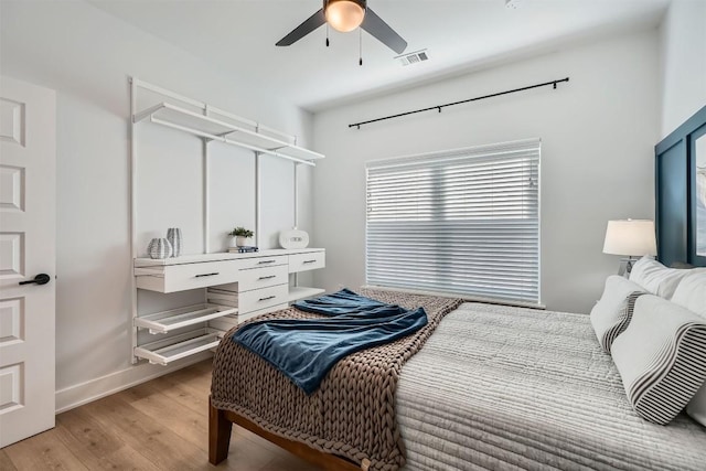 bedroom featuring ceiling fan, light wood-style flooring, visible vents, and baseboards