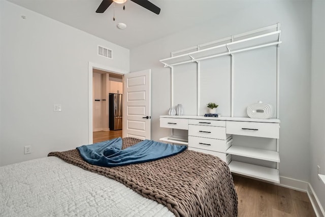 bedroom featuring baseboards, visible vents, ceiling fan, stainless steel refrigerator, and wood finished floors