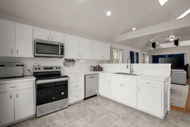 kitchen with appliances with stainless steel finishes, open floor plan, a sink, vaulted ceiling, and a peninsula