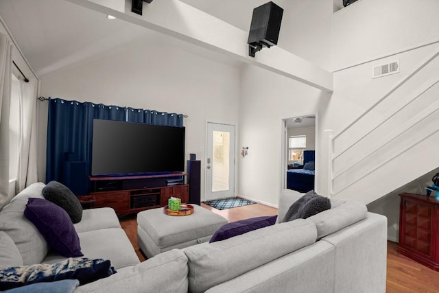 living area with high vaulted ceiling, visible vents, beamed ceiling, and wood finished floors