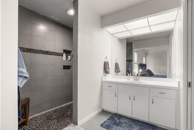 bathroom with a walk in shower, tile patterned flooring, vanity, and baseboards