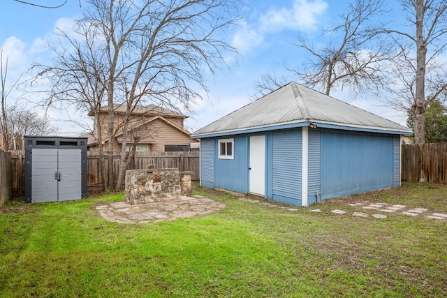 exterior space with an outbuilding, metal roof, a fenced backyard, and a lawn