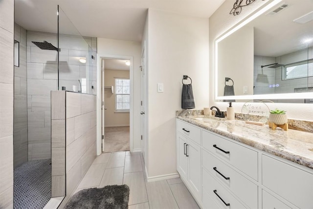 full bathroom featuring visible vents, vanity, baseboards, and a walk in shower