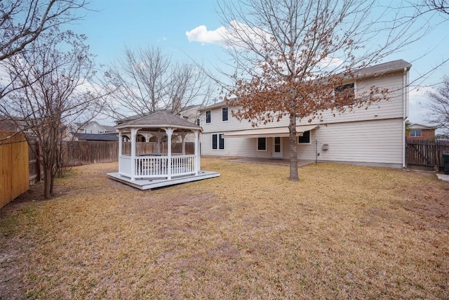 rear view of house with a gazebo, a lawn, and a fenced backyard