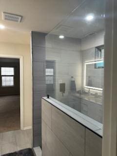 bathroom featuring visible vents and a tile shower