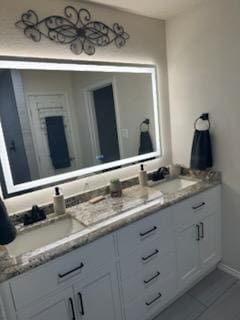 full bath featuring double vanity, tile patterned flooring, and a sink