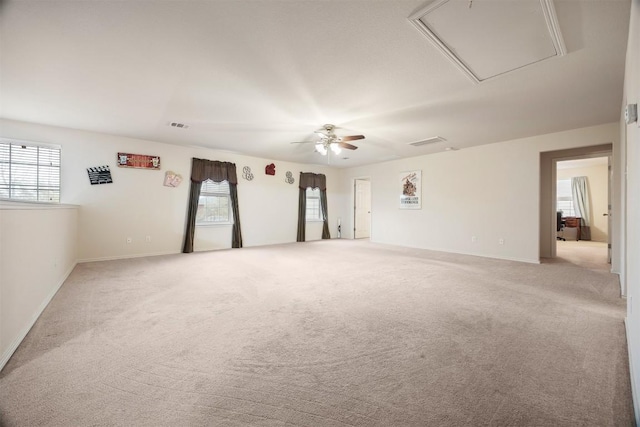 spare room with attic access, visible vents, ceiling fan, and light colored carpet