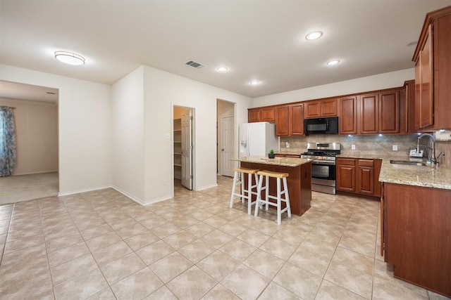 kitchen with tasteful backsplash, visible vents, stainless steel gas stove, a sink, and black microwave