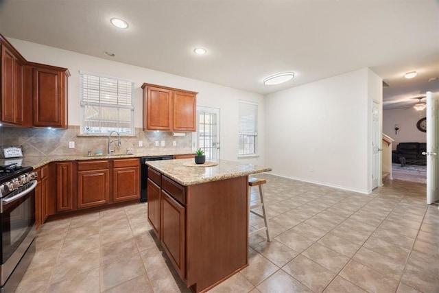 kitchen with black dishwasher, stainless steel gas range oven, a sink, a kitchen bar, and backsplash