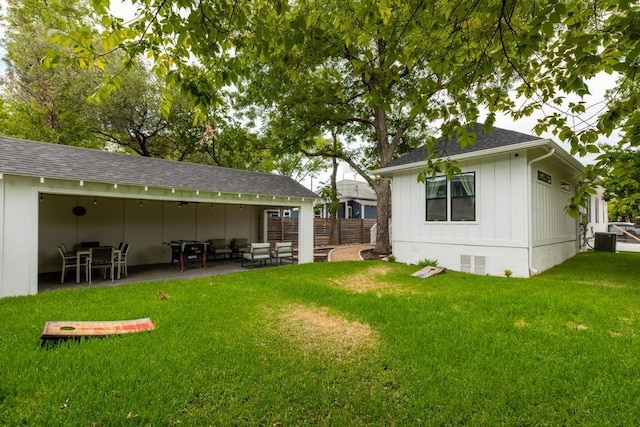 rear view of house with a lawn, board and batten siding, crawl space, a patio area, and fence