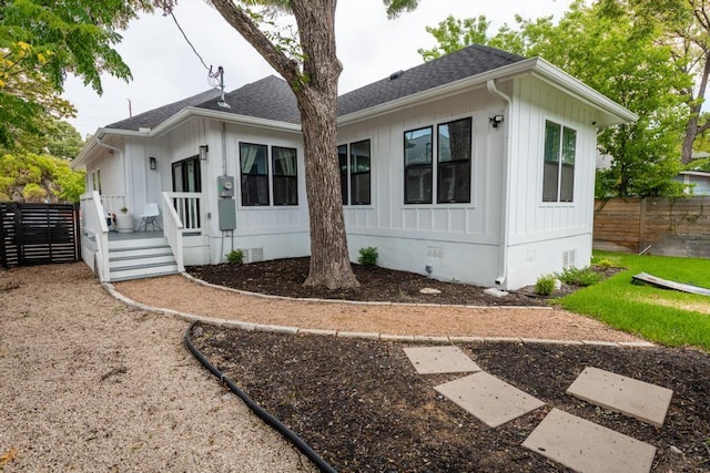 view of front facade featuring roof with shingles, crawl space, and fence