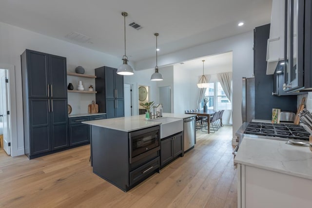 kitchen with pendant lighting, visible vents, appliances with stainless steel finishes, light wood-style floors, and a sink