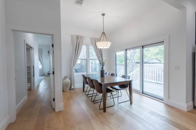 dining area with light wood-style flooring, visible vents, and baseboards