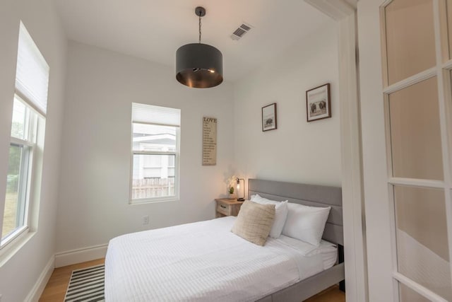 bedroom featuring visible vents, light wood-style flooring, baseboards, and multiple windows