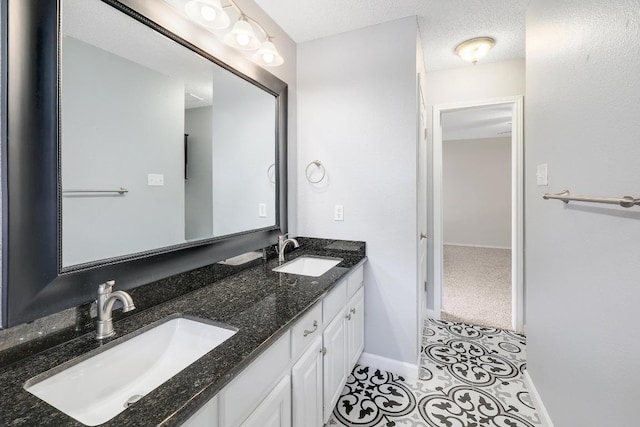 bathroom featuring tile patterned flooring, a sink, a textured ceiling, and double vanity