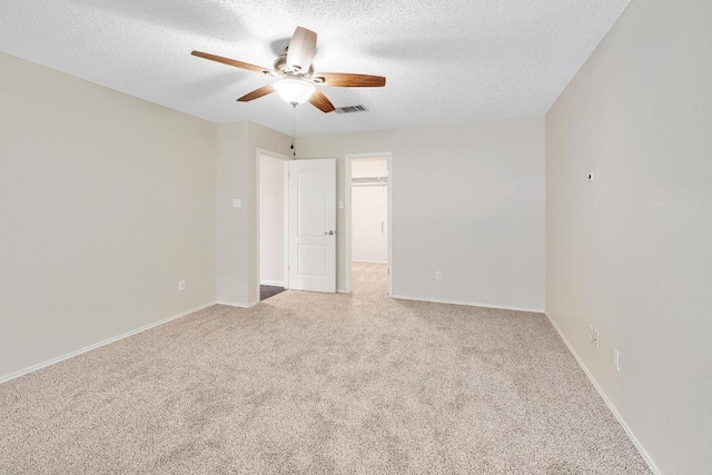 unfurnished bedroom featuring a textured ceiling, carpet, a walk in closet, and visible vents