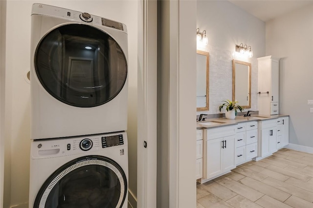 washroom with baseboards, stacked washer and dryer, a sink, and light wood-style floors