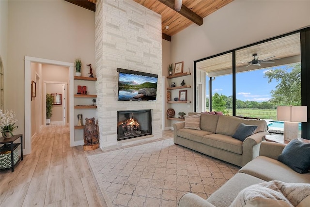 living room featuring wooden ceiling, light wood-style flooring, a fireplace, a towering ceiling, and beam ceiling