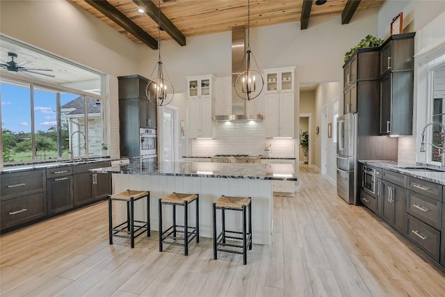 kitchen featuring dark stone countertops, stainless steel appliances, wooden ceiling, and a sink