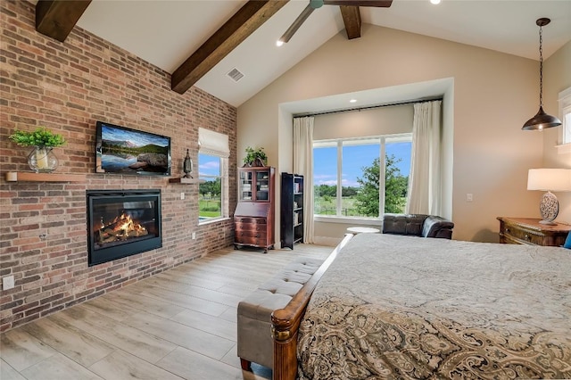 bedroom with visible vents, wood finished floors, a fireplace, high vaulted ceiling, and beam ceiling