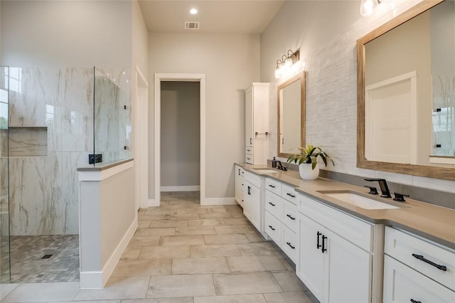 bathroom with visible vents, double vanity, a sink, and a marble finish shower