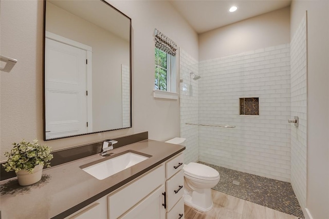 bathroom featuring vanity, a tile shower, toilet, and recessed lighting