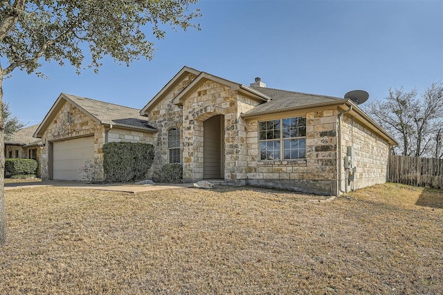 view of front of home featuring a garage, stone siding, a chimney, and fence