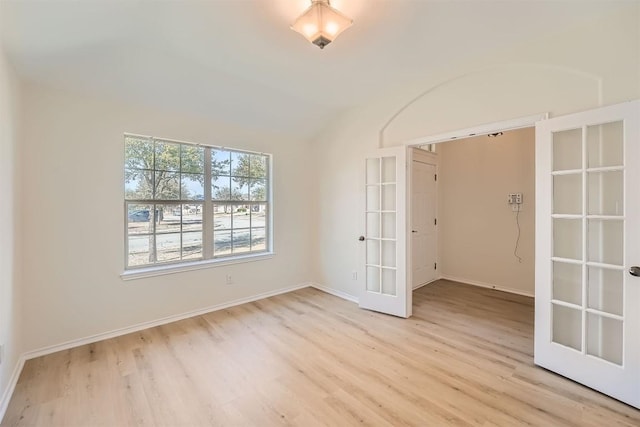 spare room with baseboards, french doors, and light wood-style floors