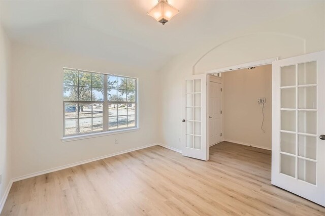 empty room featuring baseboards, light wood-style flooring, and french doors