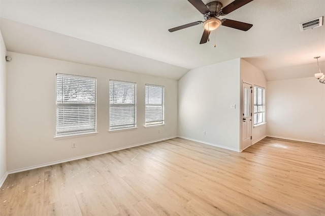spare room featuring baseboards, lofted ceiling, visible vents, and light wood-style floors