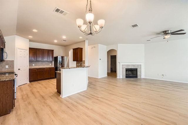 kitchen with arched walkways, visible vents, stainless steel appliances, and ceiling fan with notable chandelier