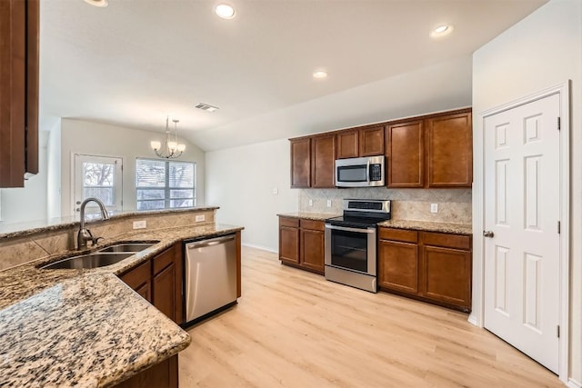 kitchen with visible vents, decorative backsplash, vaulted ceiling, stainless steel appliances, and a sink