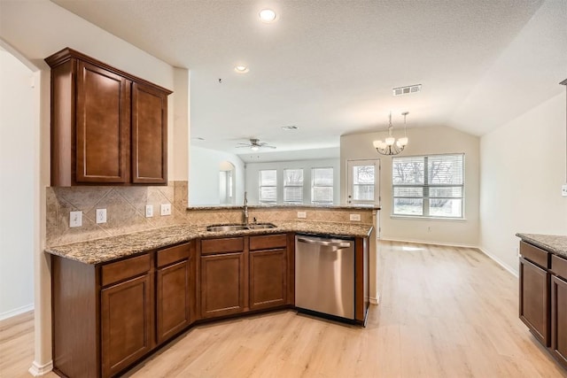 kitchen with tasteful backsplash, a peninsula, light stone countertops, stainless steel dishwasher, and a sink