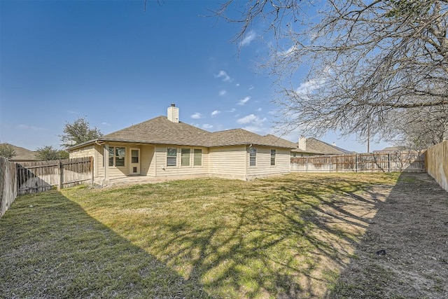 back of house featuring a patio area, a fenced backyard, a chimney, and a lawn