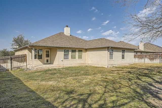 rear view of property featuring a yard, a chimney, and a fenced backyard