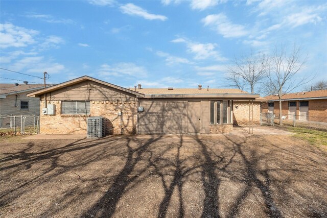 rear view of property with a patio, central AC unit, fence, and brick siding