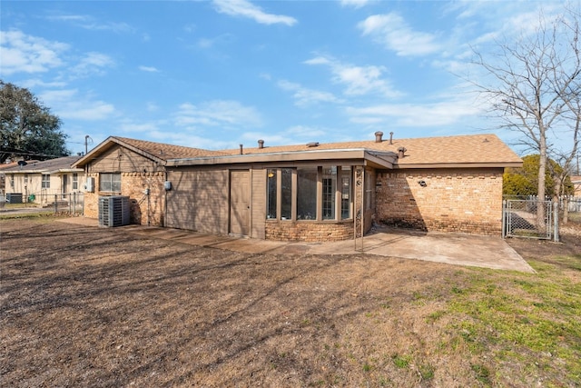 rear view of property featuring a gate, fence, a patio area, central AC, and brick siding