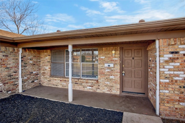 doorway to property with brick siding and a porch