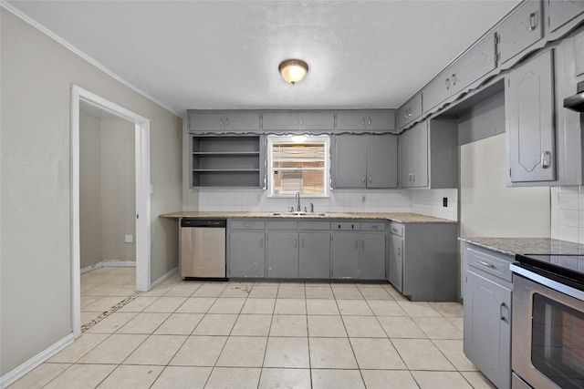 kitchen featuring baseboards, decorative backsplash, appliances with stainless steel finishes, gray cabinets, and a sink