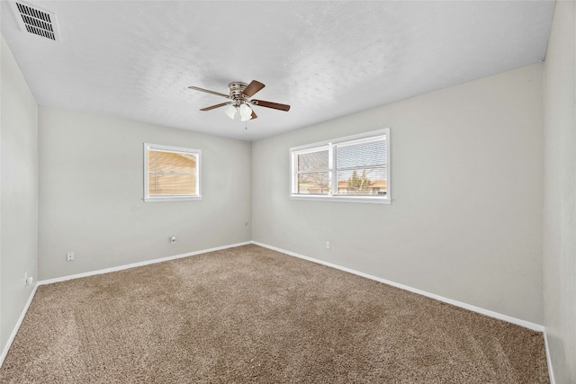 unfurnished room featuring visible vents, baseboards, a ceiling fan, carpet, and a textured ceiling