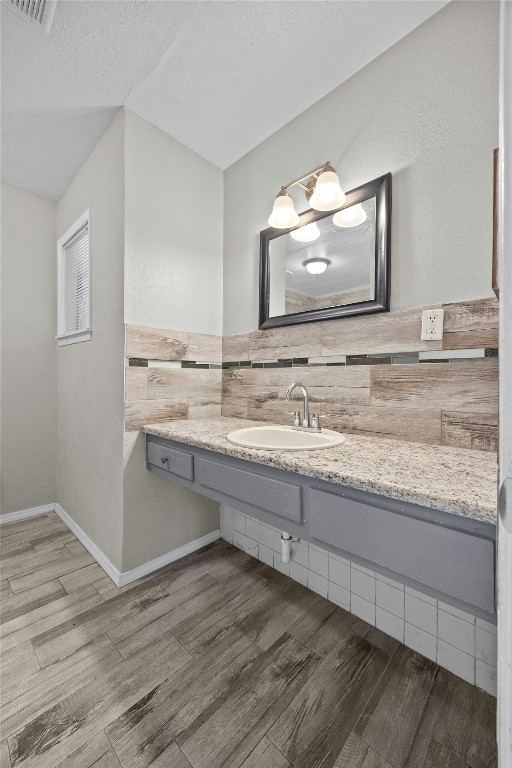 bathroom with tile walls, visible vents, a textured ceiling, vanity, and wood finished floors