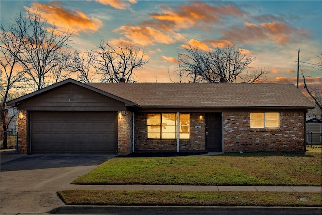 ranch-style home with a front yard, driveway, a shingled roof, a garage, and brick siding