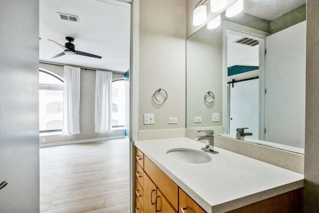 bathroom with vanity, visible vents, a ceiling fan, and wood finished floors