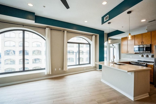 kitchen with brown cabinets, stainless steel appliances, light countertops, visible vents, and a sink