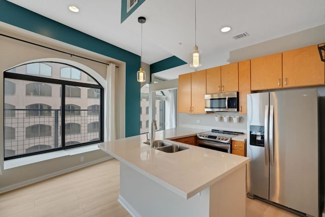 kitchen with a peninsula, a sink, visible vents, light countertops, and appliances with stainless steel finishes