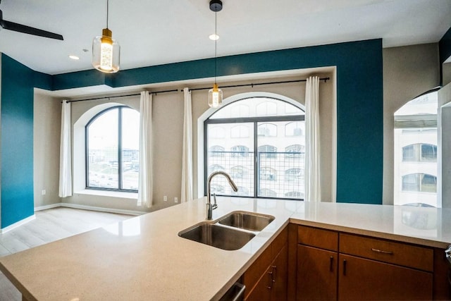 kitchen featuring light wood-type flooring, light countertops, a sink, and hanging light fixtures