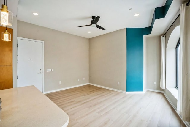 empty room featuring recessed lighting, light wood-type flooring, a ceiling fan, and baseboards