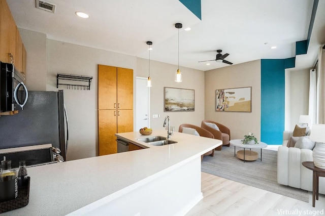 kitchen featuring a sink, visible vents, light wood-type flooring, freestanding refrigerator, and brown cabinetry