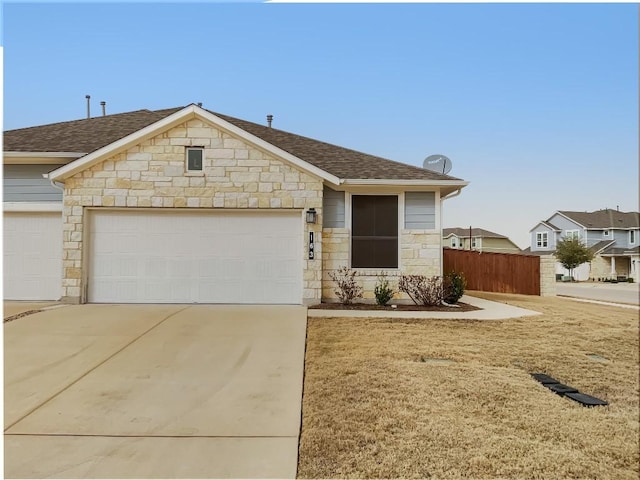 ranch-style house featuring a shingled roof, fence, a garage, stone siding, and driveway